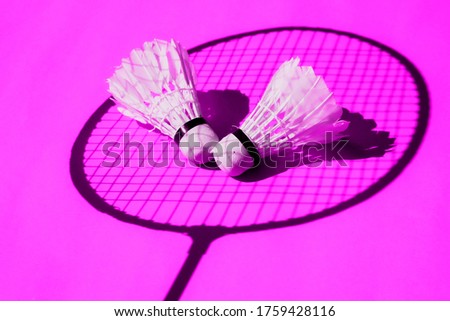 Conceptual and minimalist image of badminton rackets with very marked shadows with a modern style fluorescent pink background, sports and entertainment to enjoy on summer vacations