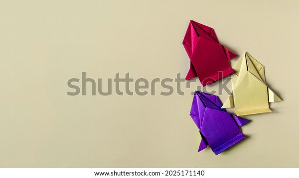 Conceptual paper cars of yellow, purple and red\
colors on a colored background close-up. Racing cars made of\
colored origami\
paper