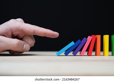 Conceptual photo of a hand starting a chain reaction with colored dominoes.
Domino effect with colored stones and copyspace.  - Powered by Shutterstock