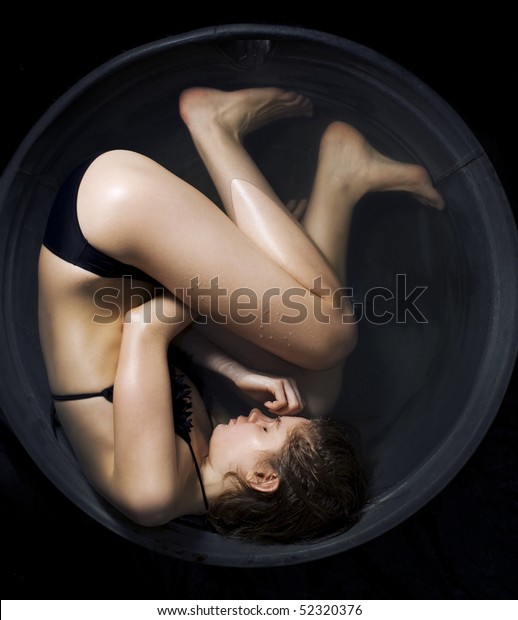 Conceptual photo of a woman curled up in a fetal\
position in the\
water.