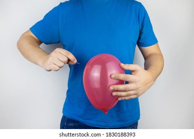 Conceptual Photography. The Man Holds A Red Ball Near His Belly, Which Symbolizes Bloating And Flatulence. Then He Brings A Needle To It To Burst The Balloon And Thus Get Rid Of The Problem.