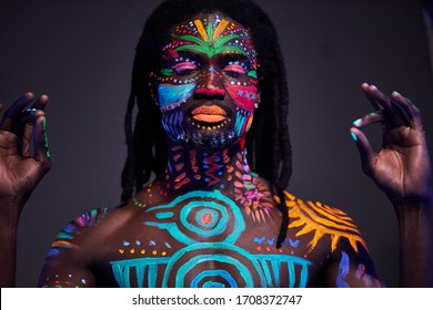 Conceptual portrait of young african calm man painted in glowing fluorescent UV colors. man stand with closed eyes, keep calm. make-up, body art concept, isolated studio shoot