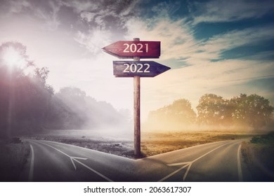 Conceptual scene choose road 2022 year or 2021. Split ways and signpost arrows showing two different courses, left and right Go ahead to the future or turn back to past. Life decision and choice  - Shutterstock ID 2063617307