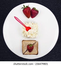 Conceptual still life with strawberry, cottage cheese and two pieces of bread in circle on black background