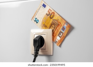 Conceptual view of euro money and home socket with plug close up. Efficiency and saving electricity concept
