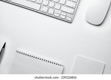 Conceptual White Ballpoint Pen, Clean Spiral Notes, Computer Keyboard And Mouse On Top Of White Table With Copy Space At The Center.