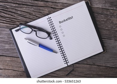 Conceptual,notebook On A Wooden Table. Open Diary, Glasses And Pen With Bucketlist Word
