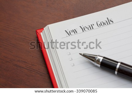 Conceptual,notebook on a wooden table. open diary and pen with new year goals words