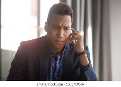 Concerned African American Businessman Talk Over Smartphone Think Of Solving Business Problem, Anxious Stressed Black Male Employee Or Boss Have Unpleasant Cellphone Conversation Hearing Bad News