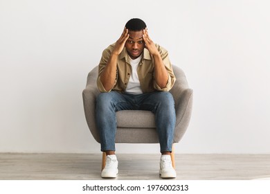 Concerned African American Guy Thinking And Worrying About Problems Touching Head Sitting In Chair Over Gray Wall Background Indoors. Depression And Male Mental Health, Stressful Life - Shutterstock ID 1976002313