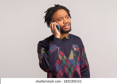 Concerned African Man With Dreadlocks Speaking Cell Phone, Discussing Problems, Free Calls, Connection. Indoor Studio Shot Isolated On Gray Background