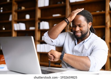 Concerned African-American young man is late, check time on a wristwatch, a sadness guy forgot about an important meeting, worried male does not have time to finish the project before the deadline