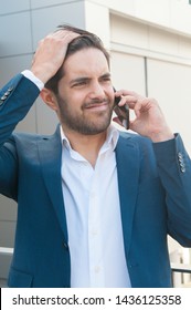 Concerned Business Man Getting Bad News From Phone Call. Upset Man In Office Suit Talking On Mobile Phone With Worried Face, Holding Head And Looking Away. Failure Concept