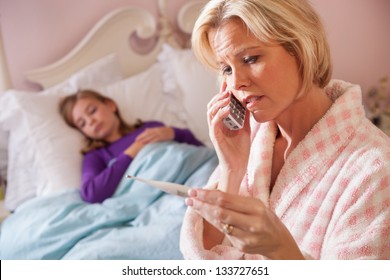 Concerned, Caucasian Blonde Mother In Bathrobe On Phone And Reading Thermometer While Her Teen-aged Daughter Lies Sick In Bed Resting.