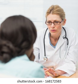 Concerned doctor talking to her patient in an office at the hospital