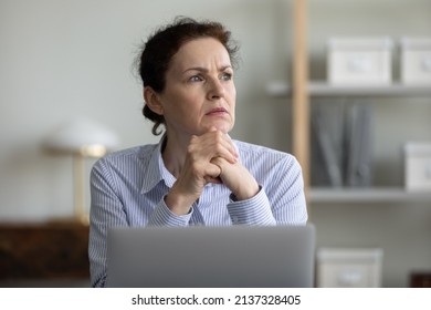 Concerned frustrated mature businesswoman sitting at laptop in office, looking away, thinking over challenging tasks, making decision, pondering on problem solving, feeling panic attack, worried - Powered by Shutterstock