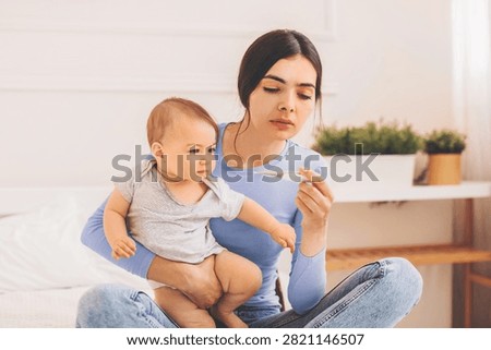 Concerned Hispanic Mother Checking Baby's Temperature At Home, Healthcare Concept