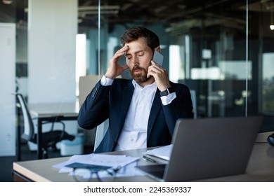 Concerned male entrepreneur talking on cellphone and touching head in stress, worried middle aged businessman suffering problems with work, having unpleasant mobile call - Powered by Shutterstock