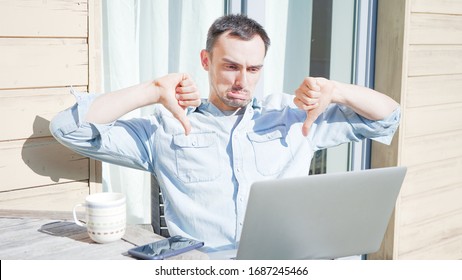 Concerned Man Having A Facetime Video Call Talking To His Colleagues. Unhappy Sad Businessman Having A Video Conference Outside On A Sunny Day. Self Isolating At Home On Balcony Drinking Coffee. 