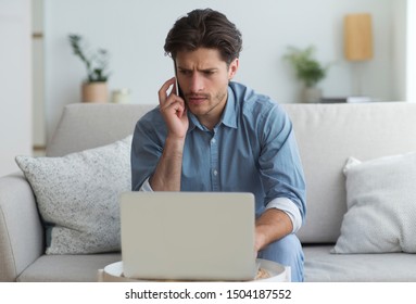 Concerned Man Talking On Mobile Phone Sitting At Laptop On Sofa Indoor. Business Calls Concept.