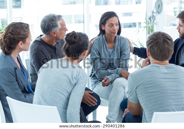 Concerned men comforting another in rehab group\
at a therapy session