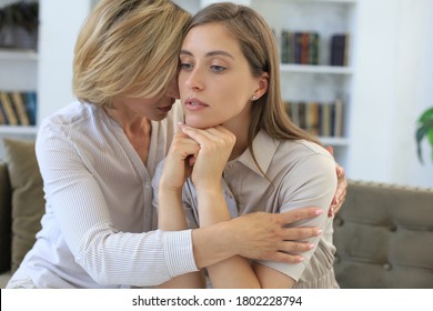 Concerned Middle Aged Mother And Adult Daughter Sit On Couch Having Serious Conversation, Listen To Her Sharing Problems