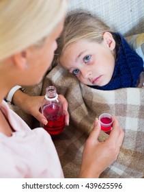 Concerned Mother Giving Mixture To Daughter With Cough