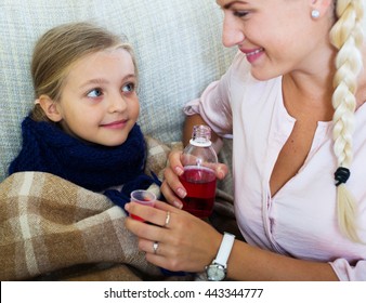 Concerned Mother Giving Mixture To Daughter With Cough