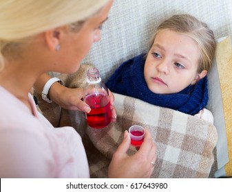 Concerned Mother Giving Mixture To Daughter With Cough