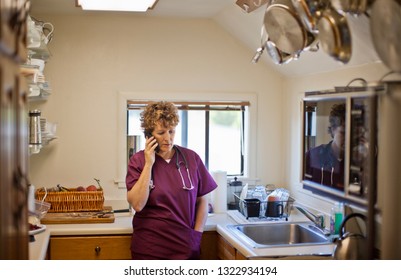 Concerned Nurse Talking On A Cell Phone In A Kitchen.