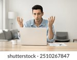 Concerned puzzled Latin freelance worker man looking at laptop with confused hand gesture. Frustrated worried computer user getting bad news, job technology failure, feeling shock, stress.