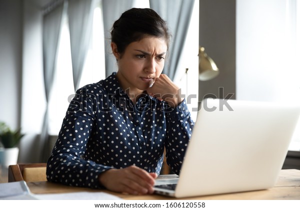 Concerned puzzled young indian woman student\
professional use look at laptop at home office feel stressed\
frustrated about computer software problem worried of technology\
negative online news\
concept