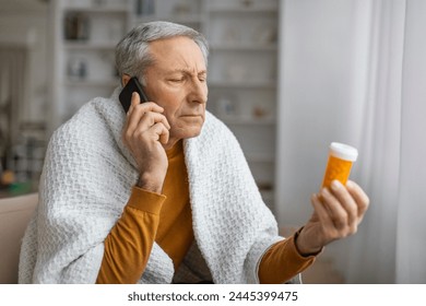 Concerned senior man looks at prescription bottle while using smartphone, consulting with doctor about medication - Powered by Shutterstock