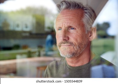 Concerned Senior Man Standing And Looking Out Of Kitchen Door Viewed Through Window - Powered by Shutterstock