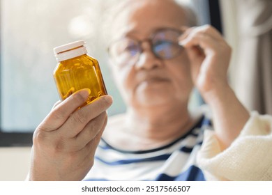 Concerned senior woman adjusting her eyeglasses for looking the a bottle of medicine. Elderly healthcare concept. Selective focus. - Powered by Shutterstock