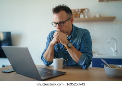 Concerned serious young man lost in thoughts in front of laptop, focused businessman thinking of problem solution, worried puzzled man looking ar laptop screen
