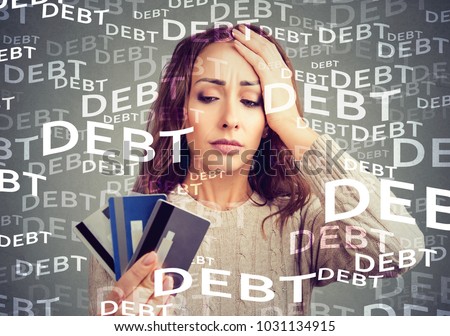Concerned woman looking at many credit cards scared with huge amount of debt.
