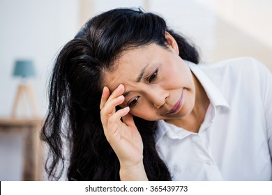 Concerned woman sitting at home with hand on head
