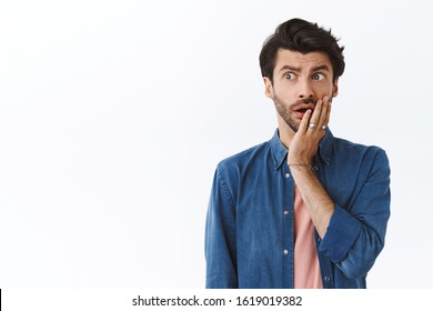 Concerned, Worried Young Caucasian Man With Beard, Touch Cheek And Look Away Alarmed, Nervously Thinking About Something Bad Happened, Gasping Standing Uneasy, Pondering What To Do With Problem