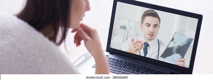 Concerned Young Doctor On Video Conference With Patient. Looking At Woman's Xray Photo