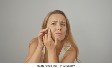 Concerned young woman inspecting her facial skin against a white backdrop. - Powered by Shutterstock