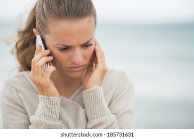 Concerned Young Woman Talking Cell Phone On Cold Beach