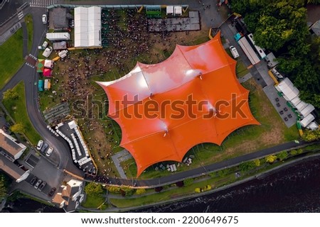 Concert of beer festival area with big red tent and service areas. Big crowd enjoy all amenities. Aerial top down view. Music event or circus in town. Entertainment industry and business.
