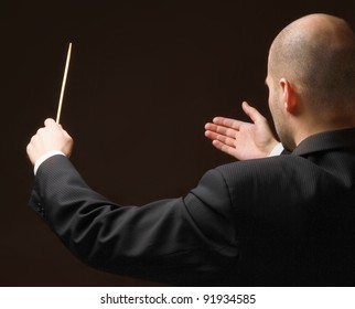 Concert Conductor With Baton Isolated On Black Background, Back-view