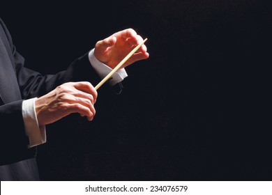 Concert Conductor Hands With A Baton Isolated On A Black Background