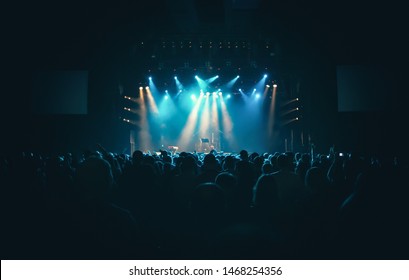 Concert Crowd In Club.Bright Stage In Big Nightclub Full Of Young People On Dance Floor.EDM Musical Festival Audience Waiting For The Show To Begin.Youth Entertainment Event In Crowded Music Hall