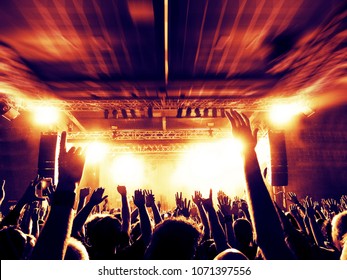 Concert Crowd In A Huge Arena With A Brightly Lit Stage