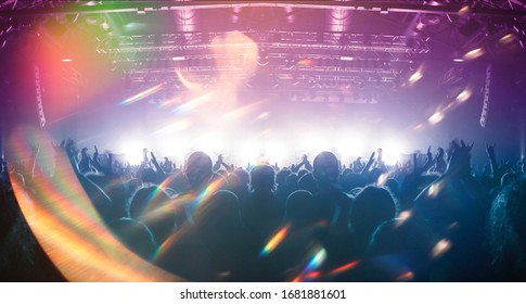 Concert crowd point of view inside a large concert hall during a music festival, the lit stage is visible. - Shutterstock ID 1681881601