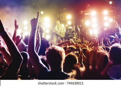 Concert Crowd. Silhouettes young people in front of bright stage lights. Band of rock stars