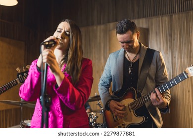 Concert duo - caucasian young adult vocalist and mid adult guitarist standing near to each other. Recording studio interior. High quality photo